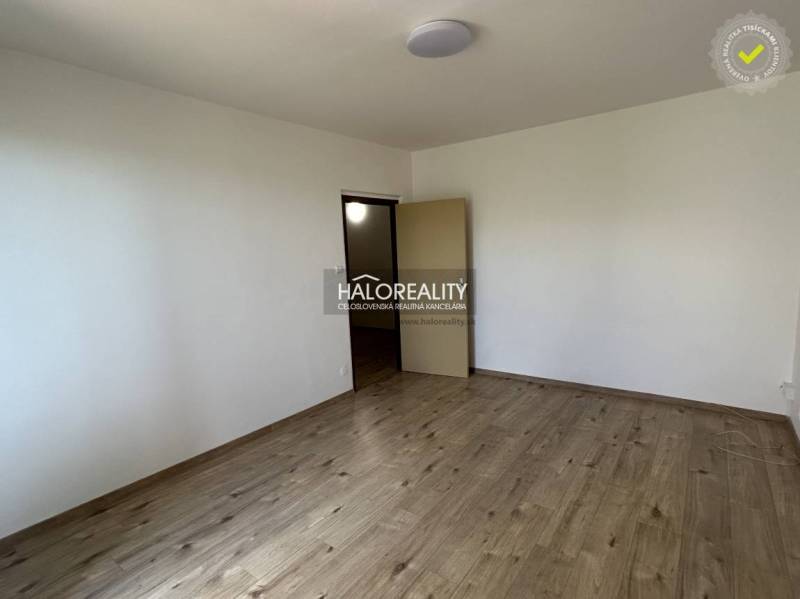 An empty room with wooden flooring in a 3-room apartment, white walls, open doors.