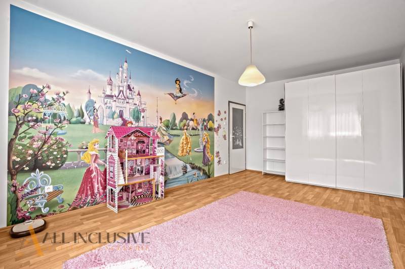 Children's room with fairy tale wallpaper in a 2-room apartment, white furniture and a pink carpet.