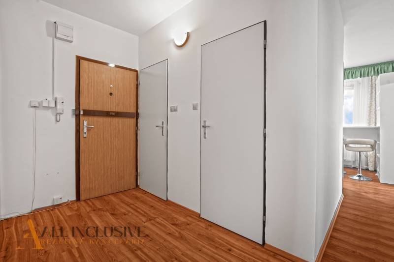 Entrance hallway in a 2-room apartment with wooden flooring and white walls.