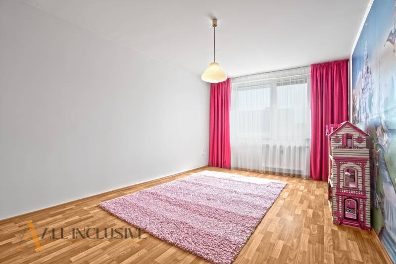 A children's room in a two-room apartment with a pink carpet and curtains.