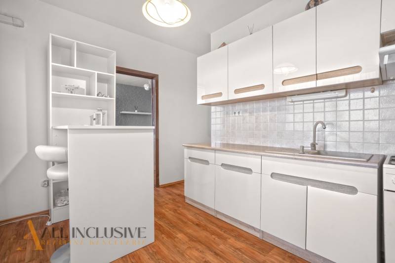 White kitchen with wooden floor and bar counter in a 2-room apartment.