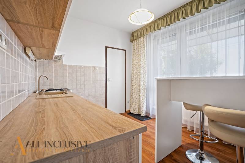 A kitchen in a 2-room apartment with a wooden countertop and high stools.