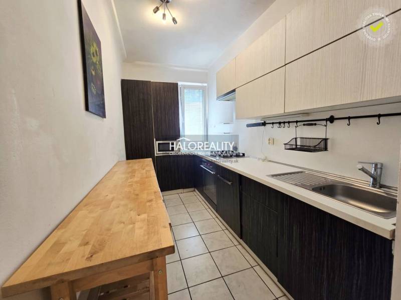 A kitchen with light furniture and a dark countertop in a 3-room apartment.