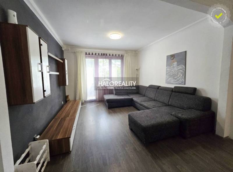 Living room in a 3-room apartment with a large sofa, wooden floor, and wall unit.