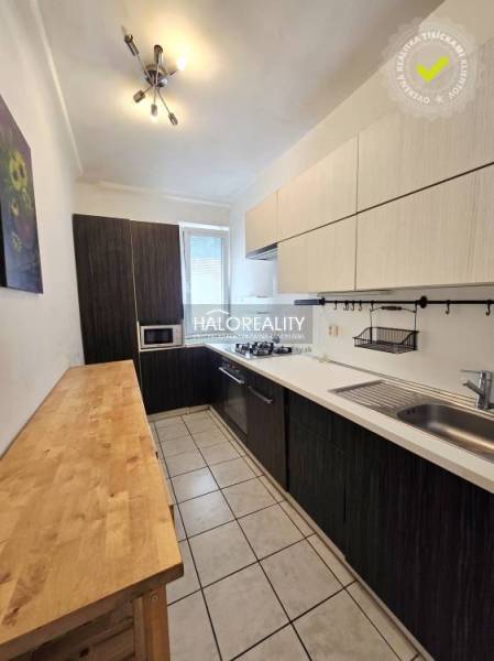 A kitchen with dark furniture, a cooktop, and a sink in a 3-room apartment.