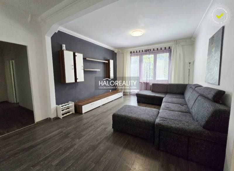 Living room in a 3-room apartment with a dark floor, gray sofa, and wall unit.
