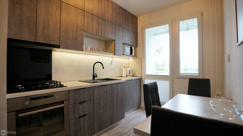 A kitchen with wooden cabinets, a gas stove, and a dining table in a 2-room apartment.