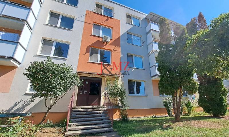 Apartment building in Tlmače, suitable for a two-room apartment, surrounded by greenery and trees.