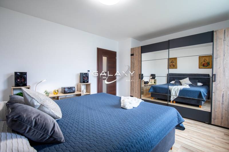 Bedroom with a mirrored wardrobe in a family house, blue bed linen, and wooden decorations.