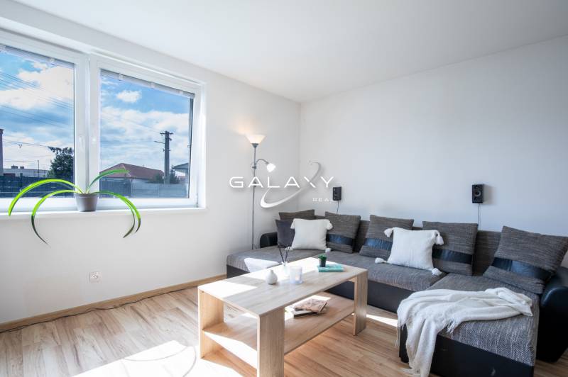 A bright living room in a family house with a comfortable sofa, a table, and a large window.