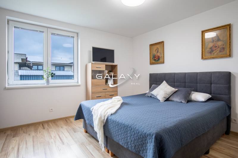 Bedroom in a family house with a double bed, paintings, and a window.