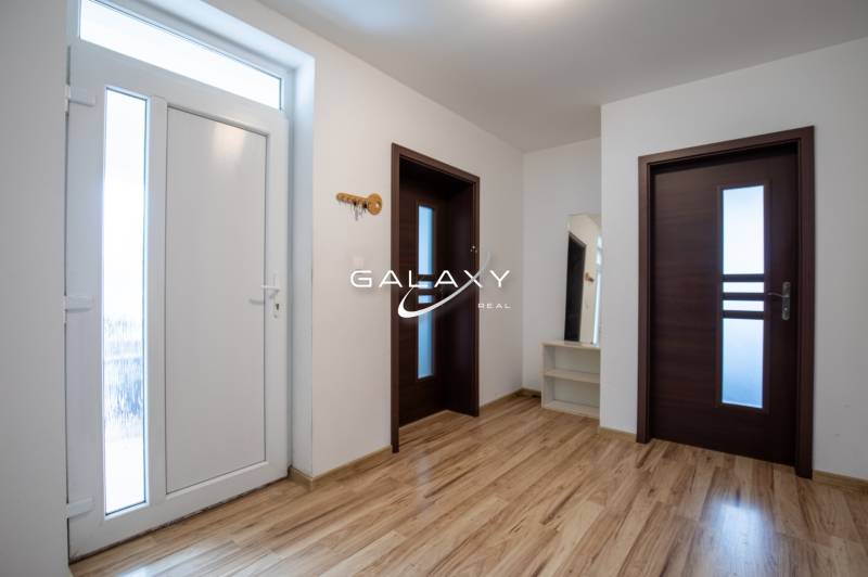 A bright hallway with white walls, wooden doors, and a mirror in a family house.