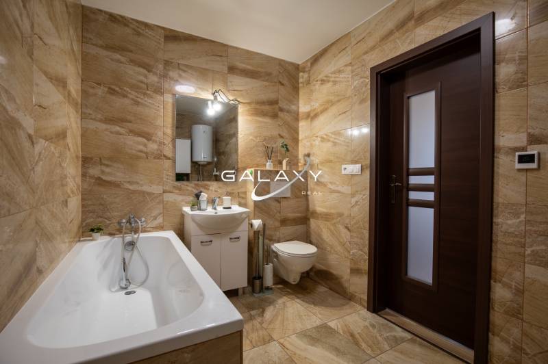 A bathroom in a family house with a bathtub, sink, and toilet in warm tile shades.