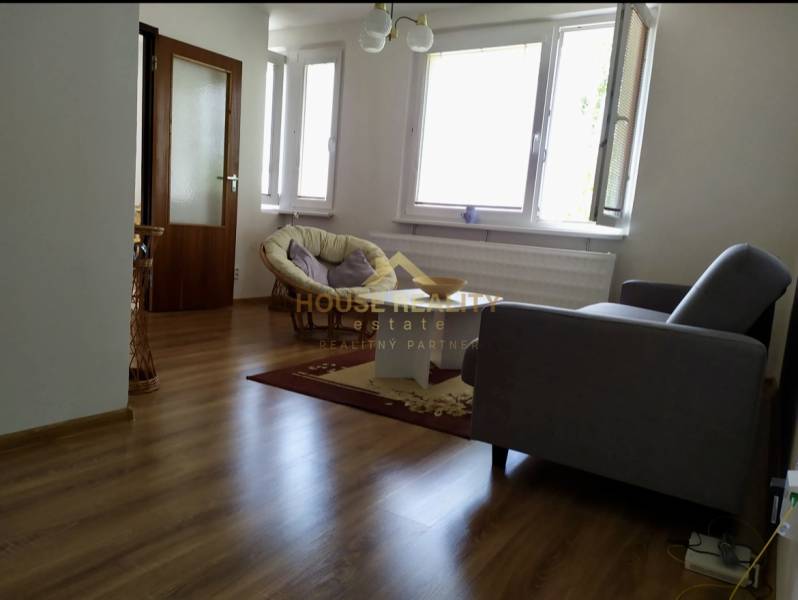 Living room in a one-room apartment with wooden flooring, a sofa, and large windows.
