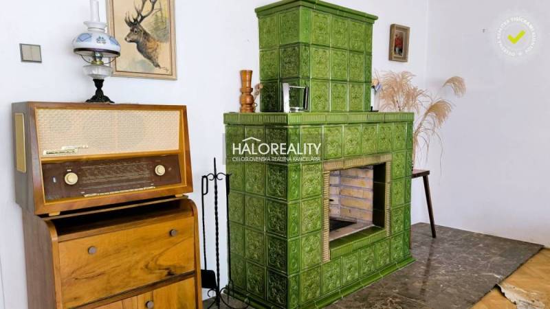 Green tiled stove, vintage radio, and decorations in the interior of a family house.