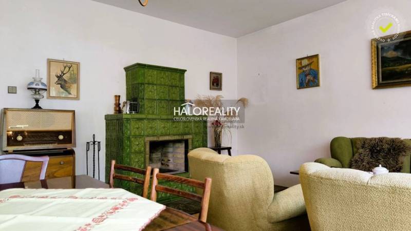 Living room in a family house with a tiled stove, retro furniture, and paintings on the walls.