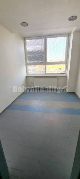 Small office with a large window, blinds, and a radiator, available for rent.