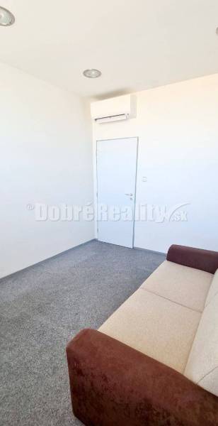 Office with white walls, carpet, air conditioning, and a sofa in the bottom right corner.