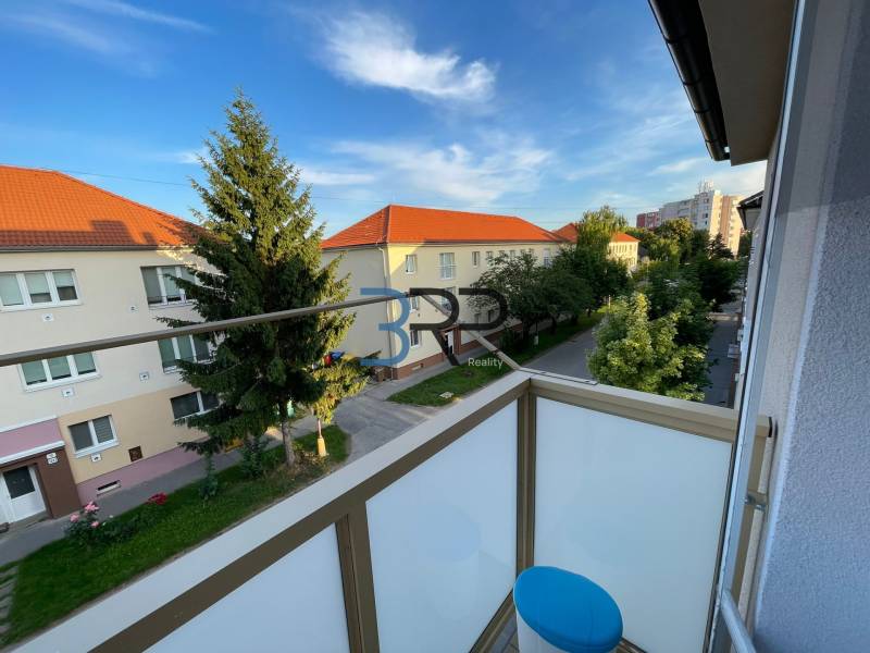 The balcony of a 2-room apartment on Hurbanova Street in Skalica with a view of trees and buildings.