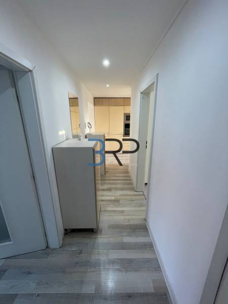 A hallway in a 2-room apartment with wooden flooring and white walls.