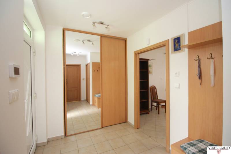 Entrance hallway of a family house with tiles, a mirror, and wooden furniture.