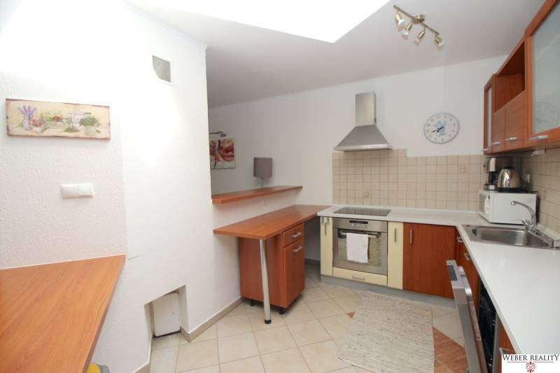 A kitchen in a family house with appliances, a wooden cabinet, and a tiled wall.