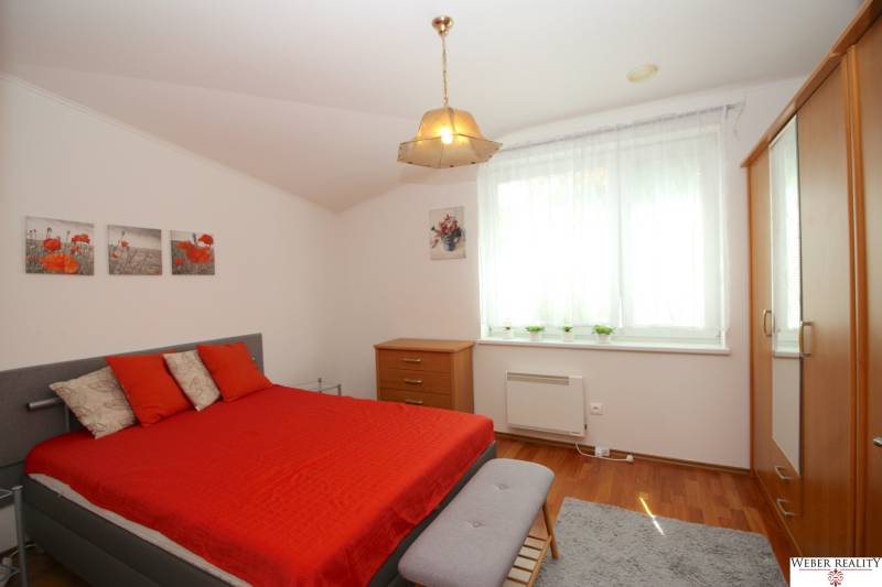 A bedroom in a family house with a double bed, wooden furniture, and red accessories.