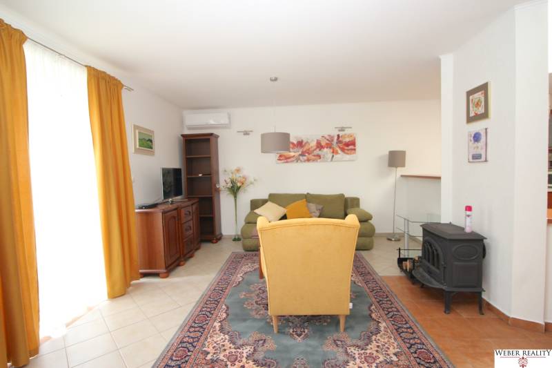 Living room with floral paintings, a yellow armchair, and a green sofa in a family house.
