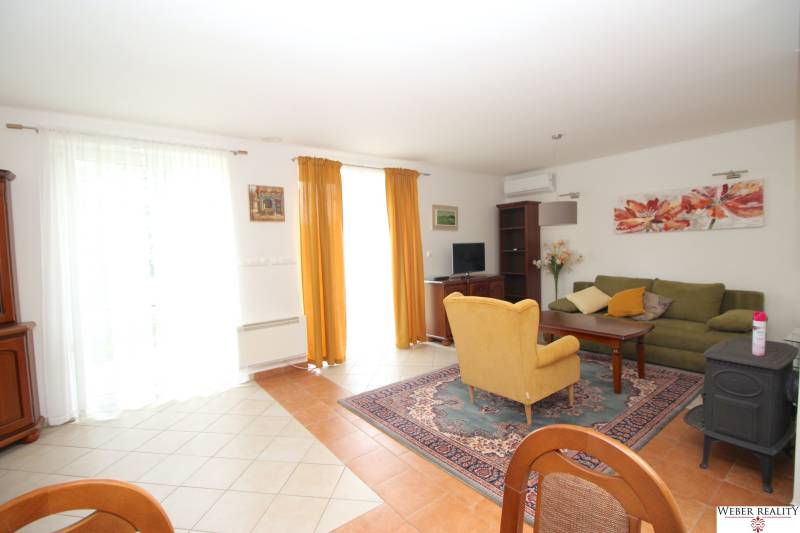 Living room in a family house with a sofa set and an armchair, decorated with paintings and curtains.