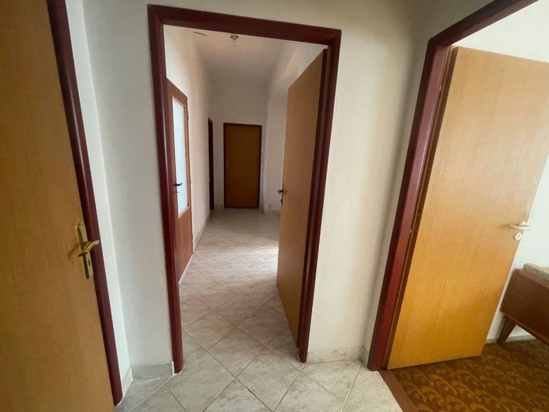 Interior of a family house with a hallway, doors, and light tiles.