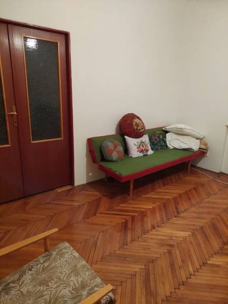 Interior of a family house with a wooden floor, a sofa, and cushions in the corner of the room.