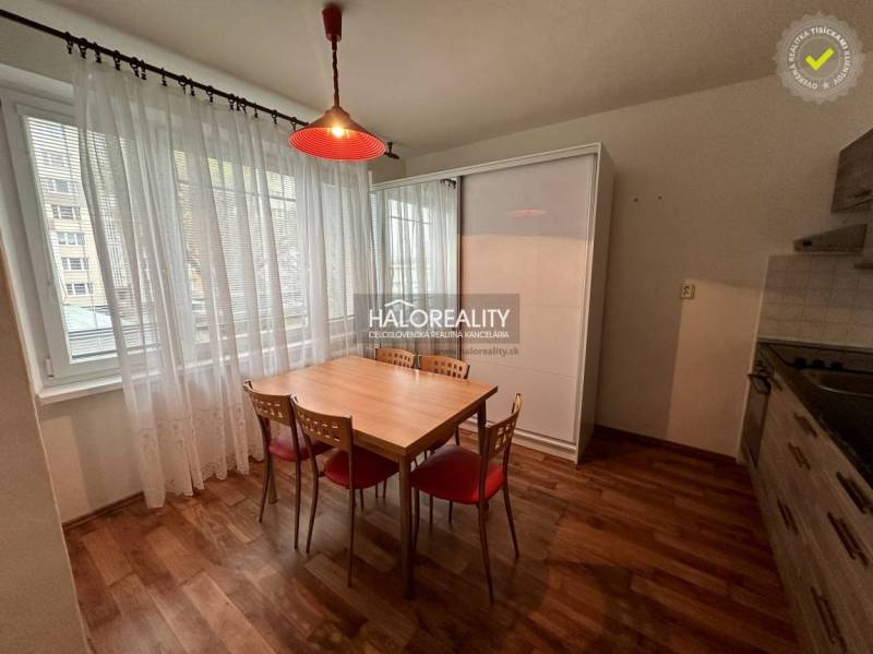 Dining area in a studio apartment with a wooden table and four chairs.