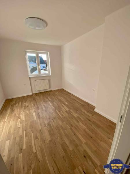 A room in a 3-room apartment with a wooden floor and white walls, a window with a view.