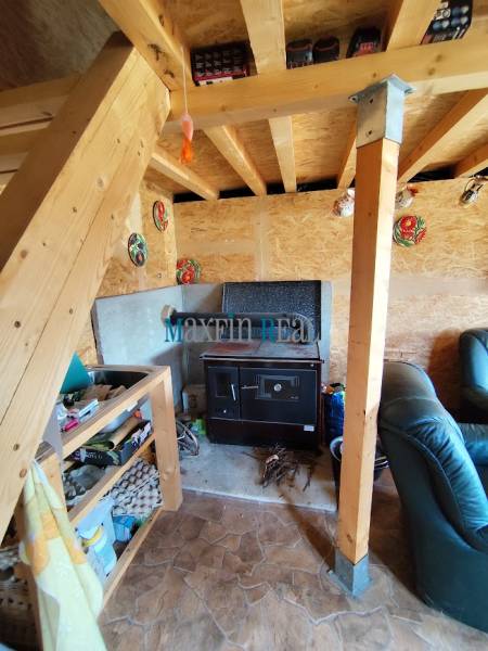 Interior with wooden stairs, a comfortable armchair, and a traditional stove. Property - housing.