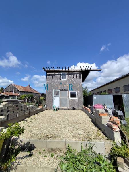 Building plot in Jelšovce suitable for living, with a garden house in the background.