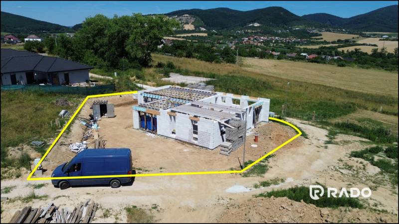 A family house construction in Trenčianske Jastrabie, surrounded by greenery and hills.