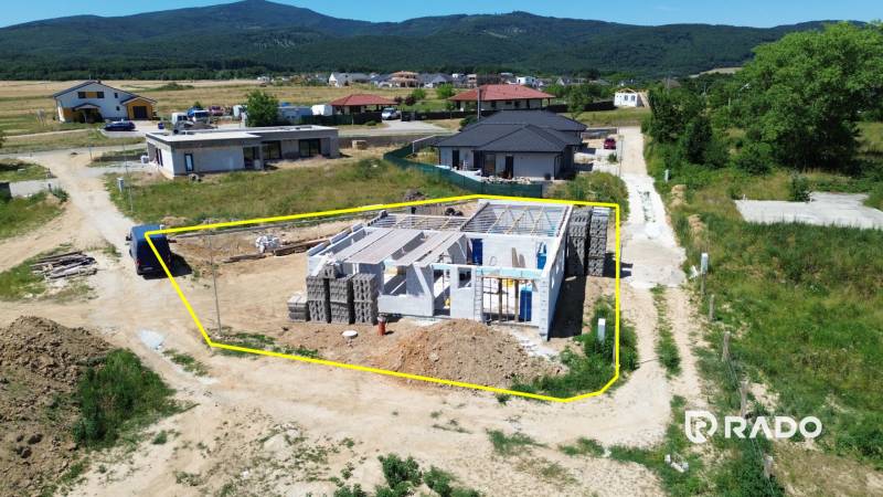 A family house construction in Trenčianske Jastrabie, surrounded by rural landscape and neighboring houses.