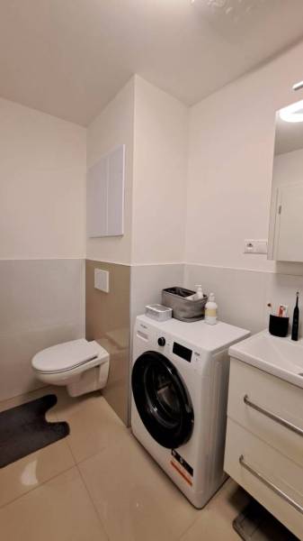 Bathroom in a 2-room apartment with a washing machine, sink, and toilet.