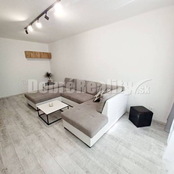Living room in a 3-room apartment with a large sofa, table, and minimalist design.