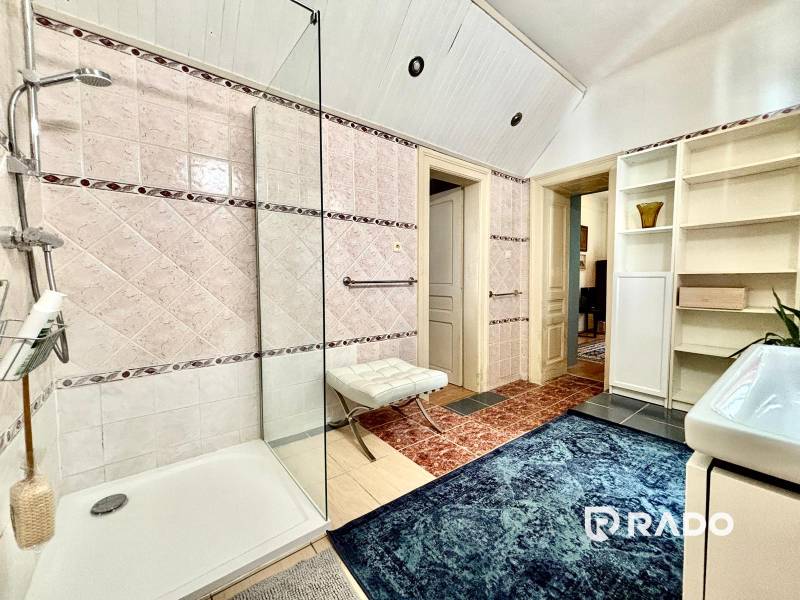 A bathroom in a 2-room apartment with a shower, carpet, and storage shelves.
