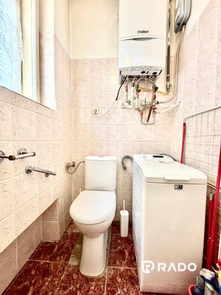Bathroom in a 2-room apartment with a toilet, washing machine, and gas boiler on the wall.