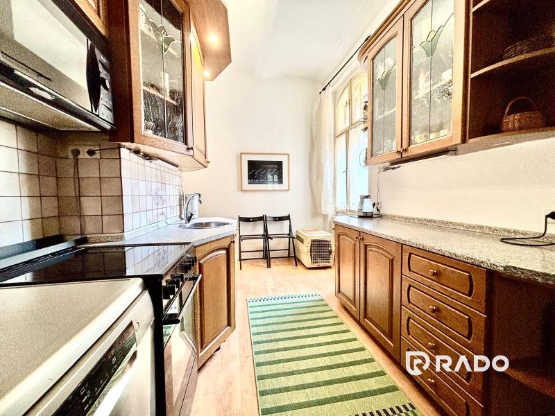 A kitchen in a 2-room apartment with wooden cabinets, a stove, and a spacious countertop.