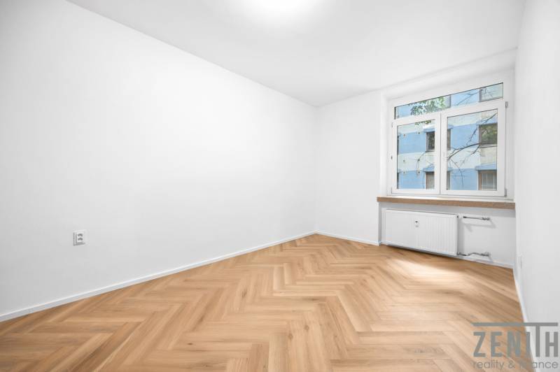 A room in a 3-room apartment with wooden flooring and a large window.