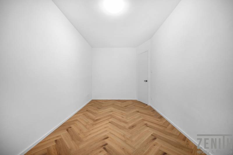 An empty room with white walls and wooden flooring in a 3-room apartment.