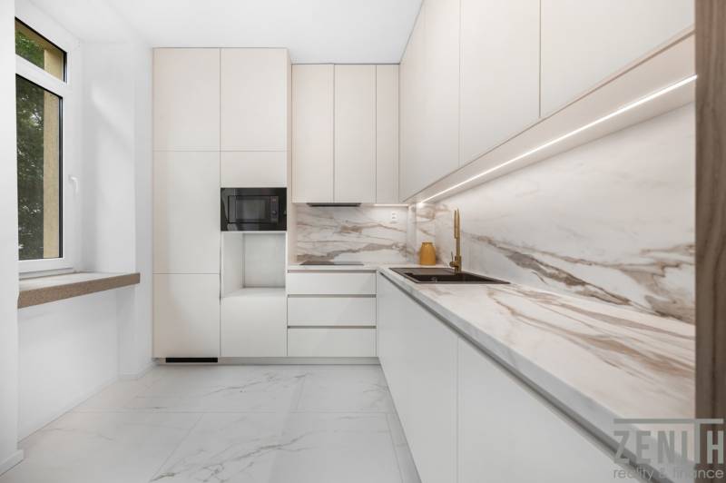 White kitchen with a marble countertop and sink in a 3-room apartment.