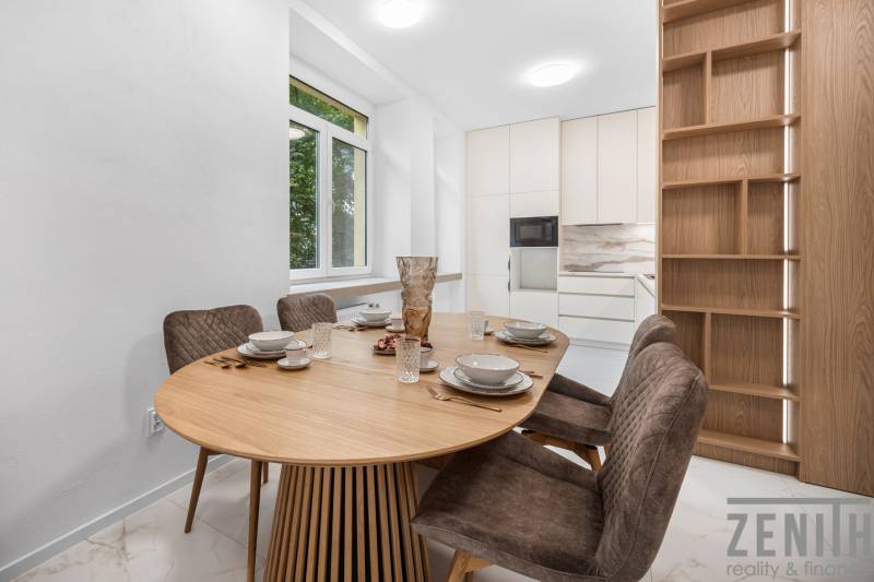 A bright kitchen with an oval table, four chairs, and a large window in a three-room apartment.