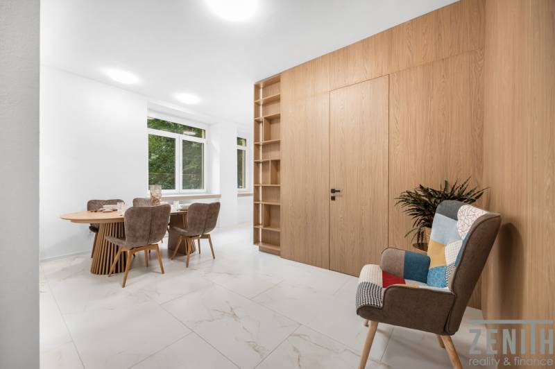 Dining room in a 3-room apartment with a wooden table, chairs, and a decorative armchair.