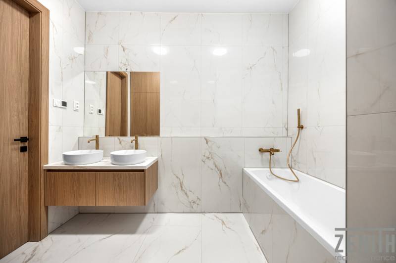 Bathroom with a mirror, double sink, and bathtub in a 3-room apartment.