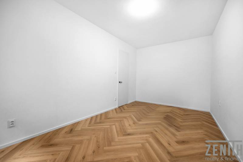 An empty room in a 3-room apartment with herringbone parquet flooring.