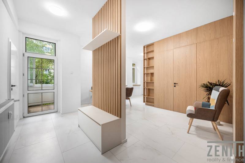 A bright interior of a 3-room apartment with wooden elements and a relaxing chair.